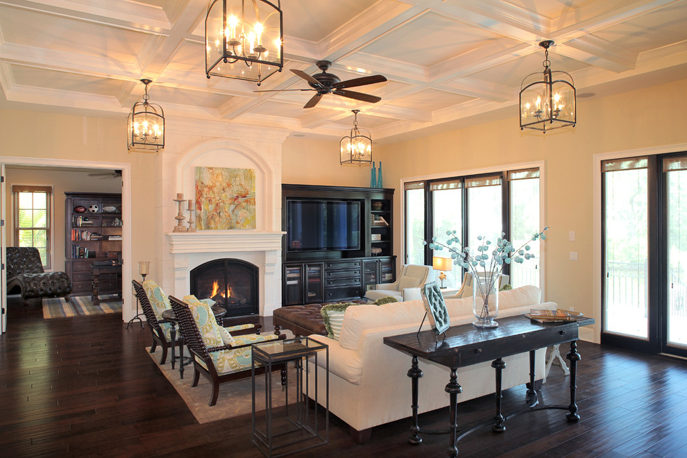 Example of a tuscan living room design in Tampa with beige walls, a standard fireplace and a media wall