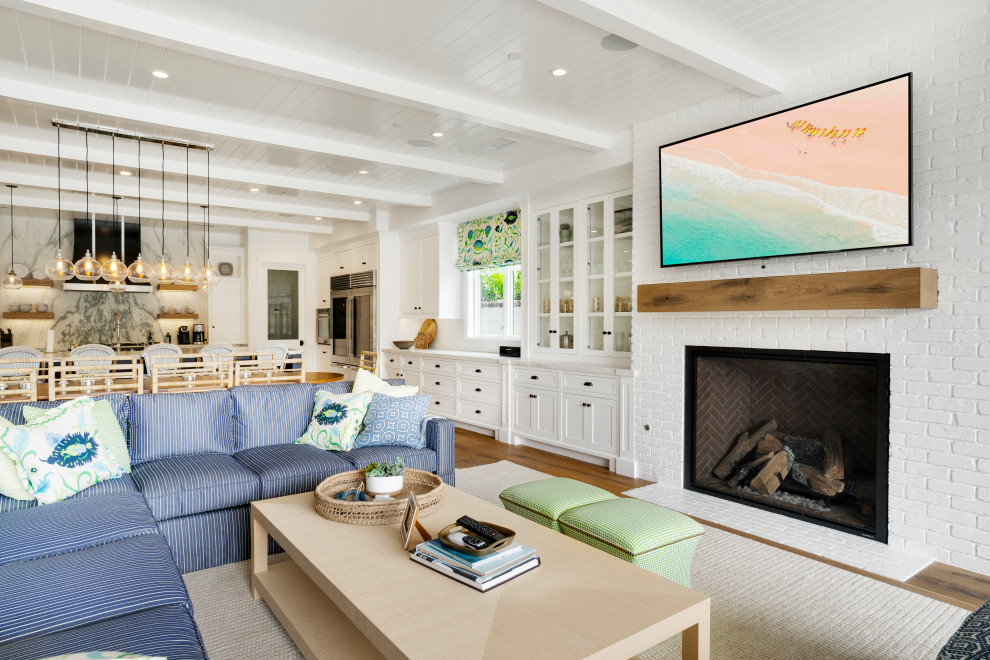 Inspiration for a mid-sized coastal open concept light wood floor living room remodel in Orange County with white walls, a standard fireplace, a brick fireplace and a wall-mounted tv