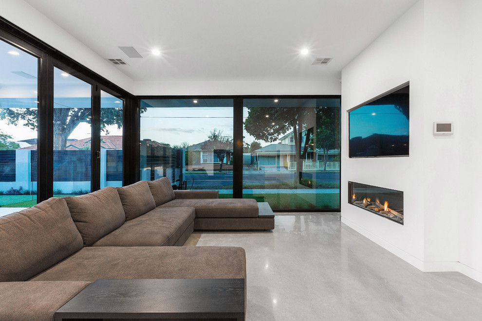 Inspiration for a mid-sized contemporary open concept concrete floor and gray floor living room remodel in Melbourne with white walls, a standard fireplace, a plaster fireplace and a wall-mounted tv