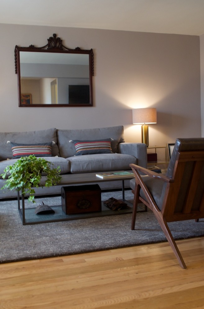 Diseño de salón abierto actual pequeño con paredes grises, suelo de madera clara y televisor colgado en la pared
