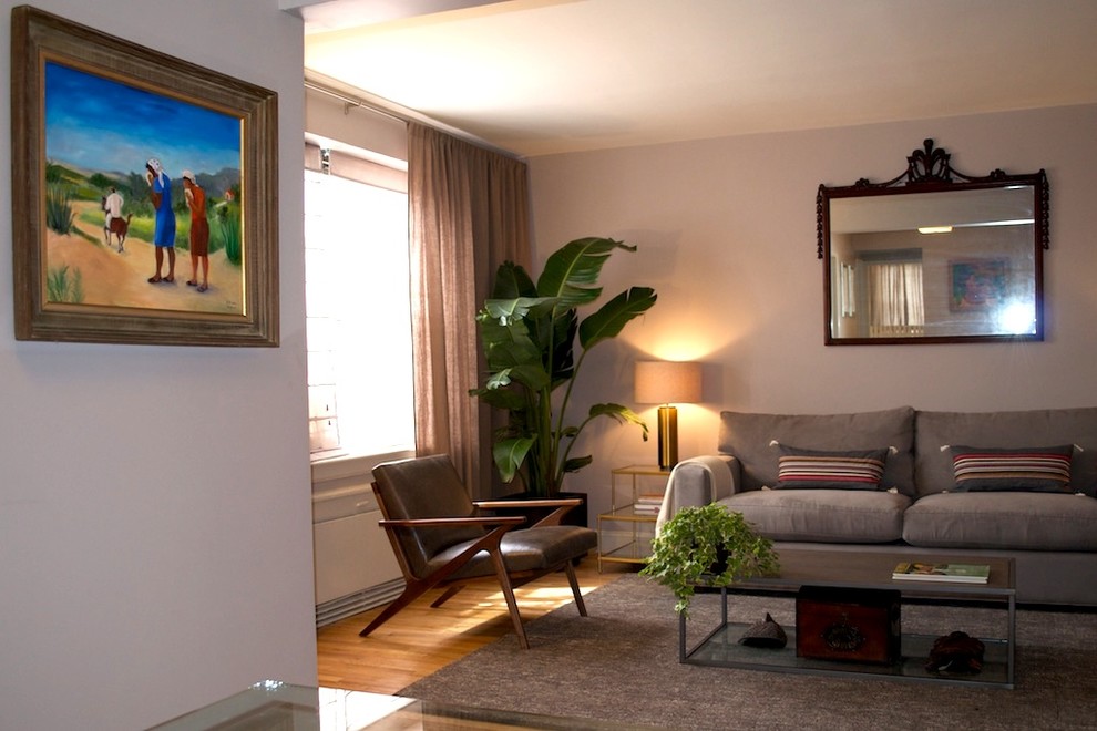 Esempio di un piccolo soggiorno contemporaneo aperto con pareti grigie, parquet chiaro e TV a parete