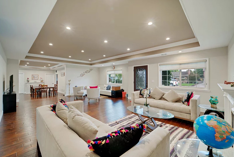 Design ideas for a large classic open plan living room in San Francisco with white walls, medium hardwood flooring, a standard fireplace, a tiled fireplace surround, a freestanding tv and brown floors.