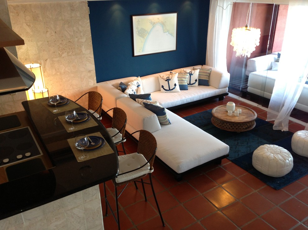 Diseño de salón con barra de bar abierto costero de tamaño medio sin chimenea y televisor con paredes azules, suelo de baldosas de terracota y suelo rojo