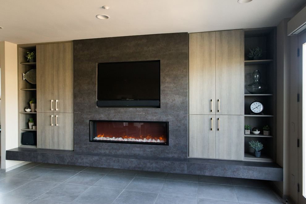 Пример оригинального дизайна: большая открытая гостиная комната в современном стиле с полом из керамической плитки, горизонтальным камином, фасадом камина из металла, телевизором на стене и серым полом