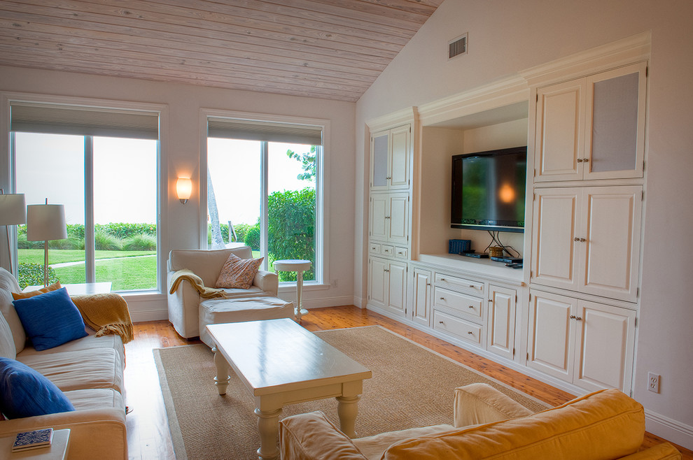 Mittelgroßes, Offenes Maritimes Wohnzimmer mit weißer Wandfarbe, braunem Holzboden, Kamin, Kaminumrandung aus Stein und Multimediawand in Miami