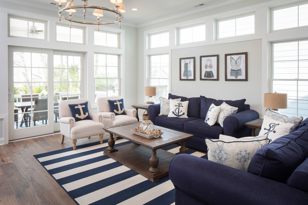 Стильный дизайн: гостиная комната в морском стиле с серыми стенами, темным паркетным полом, коричневым полом и синим диваном - последний тренд