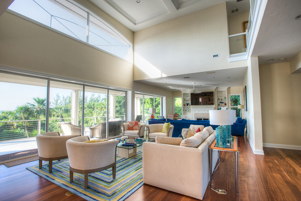 Example of a mid-sized beach style open concept medium tone wood floor living room design in Miami with beige walls, a standard fireplace, a tile fireplace and a wall-mounted tv