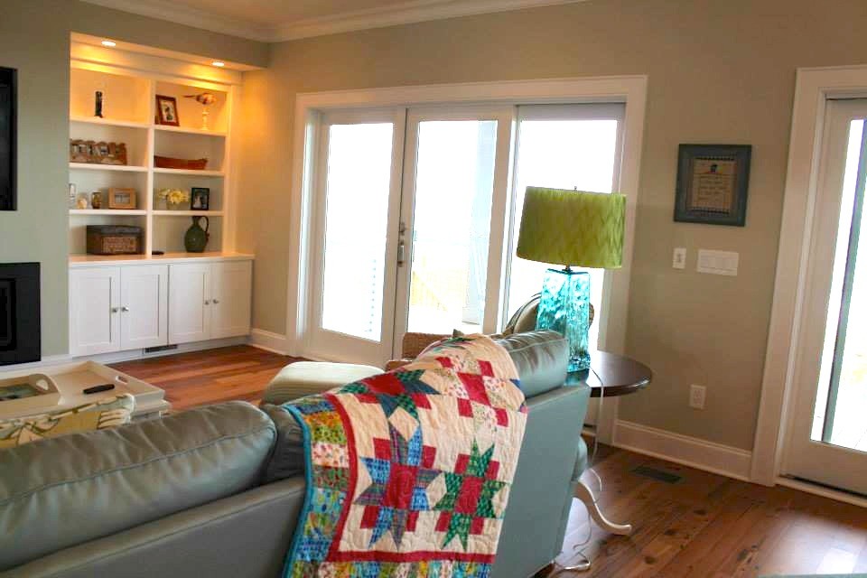 На фото: открытая гостиная комната среднего размера в морском стиле с бежевыми стенами, темным паркетным полом, горизонтальным камином, фасадом камина из металла и красным полом без телевизора