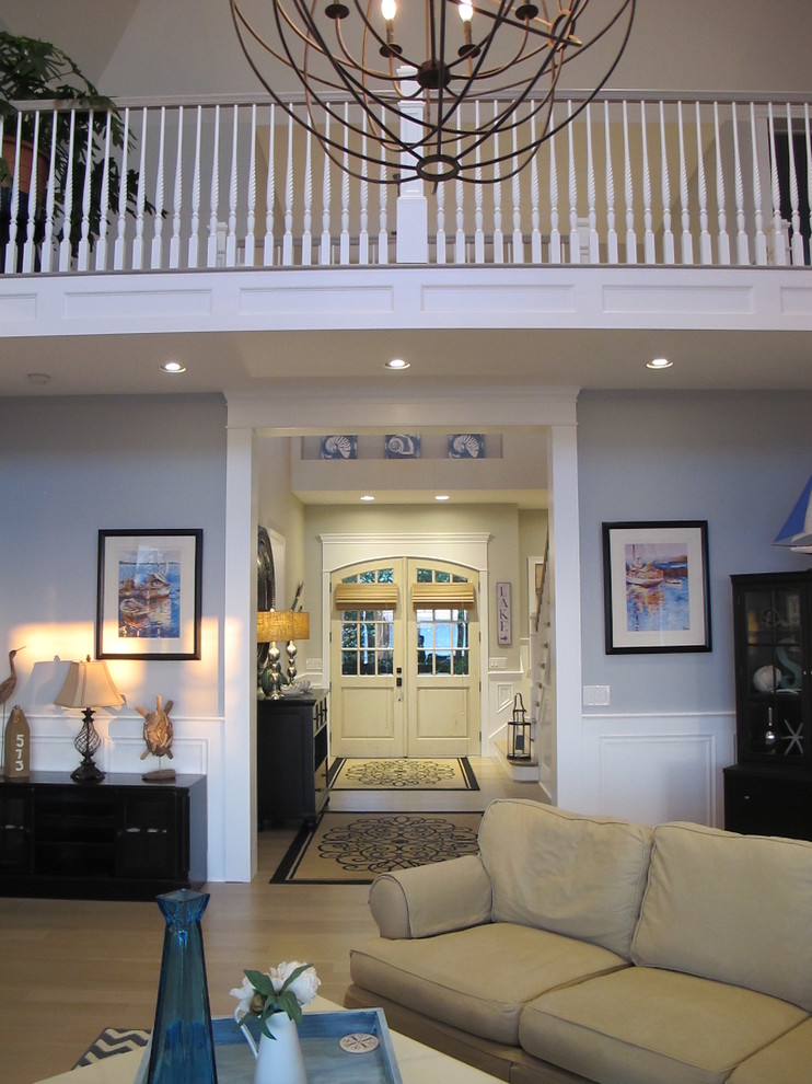 Réalisation d'un grand salon marin ouvert avec une salle de réception, un mur bleu, parquet clair, cheminée suspendue, un manteau de cheminée en pierre et un téléviseur fixé au mur.