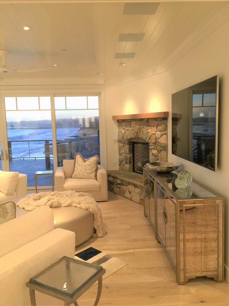 Свежая идея для дизайна: открытая гостиная комната в морском стиле с белыми стенами, стандартным камином, фасадом камина из камня и телевизором на стене - отличное фото интерьера