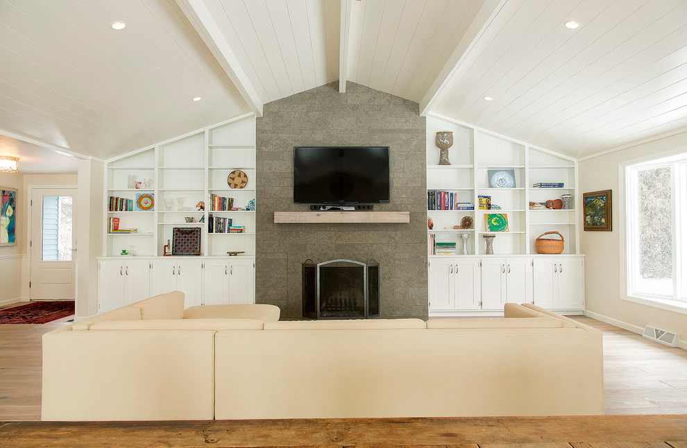 Идея дизайна: большая открытая гостиная комната в стиле кантри с белыми стенами, светлым паркетным полом, стандартным камином, фасадом камина из камня и телевизором на стене