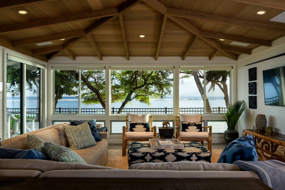 ハワイにある高級な中くらいなビーチスタイルのおしゃれなLDK (白い壁、磁器タイルの床、壁掛け型テレビ、グレーの床、表し梁、パネル壁) の写真