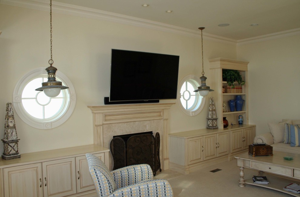 Foto di un grande soggiorno stile marinaro con pareti beige, camino classico, cornice del camino in legno e TV a parete
