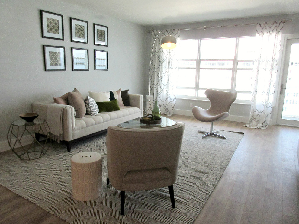 Modelo de salón abierto clásico renovado de tamaño medio con paredes grises, suelo laminado y televisor independiente