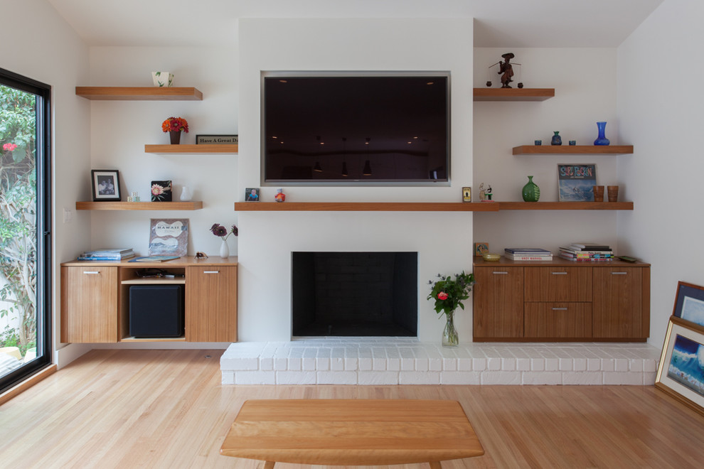 Imagen de salón abierto actual de tamaño medio con paredes blancas, suelo de madera en tonos medios, todas las chimeneas, marco de chimenea de yeso y televisor colgado en la pared