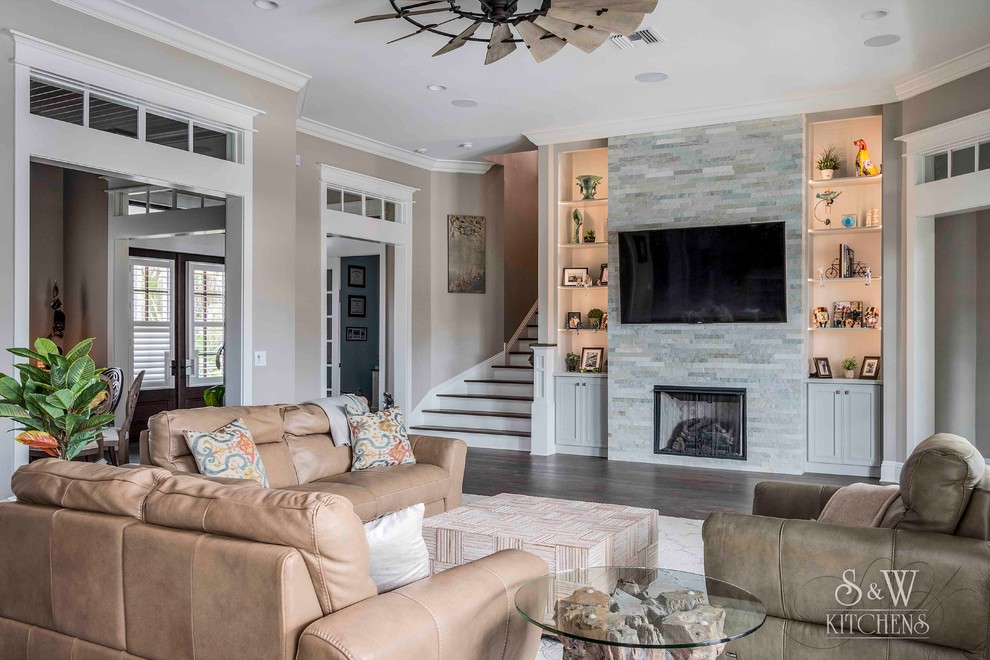 Photo of a large coastal open plan living room in Tampa with grey walls, dark hardwood flooring, a standard fireplace, a stone fireplace surround, a wall mounted tv and brown floors.