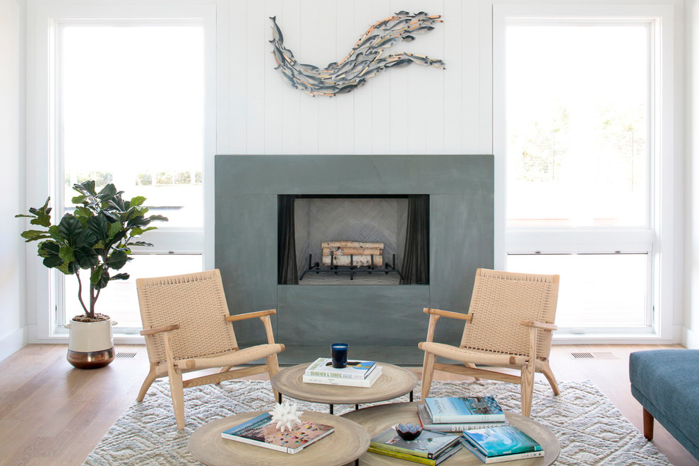 Design ideas for a coastal living room in New York with white walls, light hardwood flooring, a standard fireplace and a concrete fireplace surround.