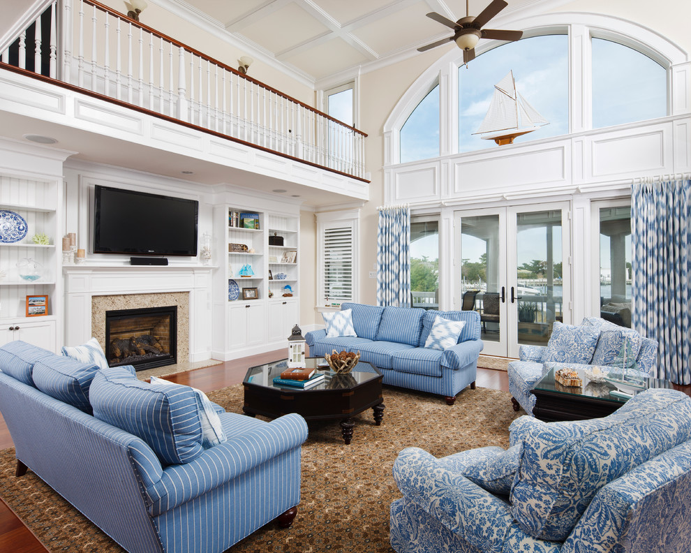 На фото: гостиная комната в морском стиле с бежевыми стенами, паркетным полом среднего тона, стандартным камином, телевизором на стене и синим диваном