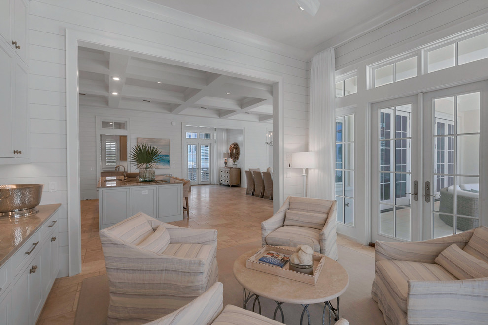 Стильный дизайн: огромная гостиная комната в морском стиле с белыми стенами, полом из травертина, стандартным камином и фасадом камина из плитки - последний тренд