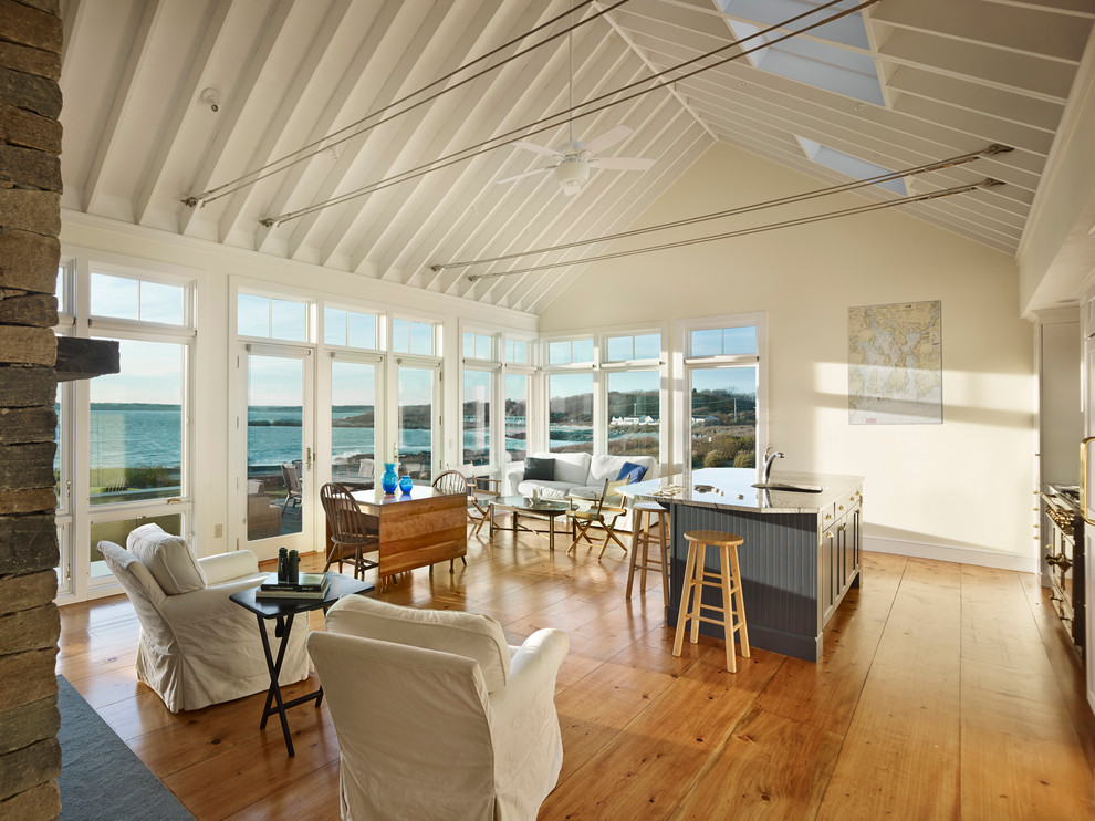 Imagen de salón abierto costero con paredes blancas y suelo de madera en tonos medios