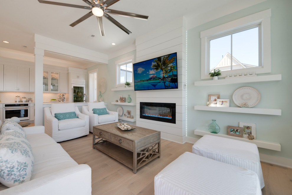 他の地域にある高級な広いビーチスタイルのおしゃれなLDK (緑の壁、淡色無垢フローリング、横長型暖炉、塗装板張りの暖炉まわり、壁掛け型テレビ、グレーの床、塗装板張りの壁) の写真