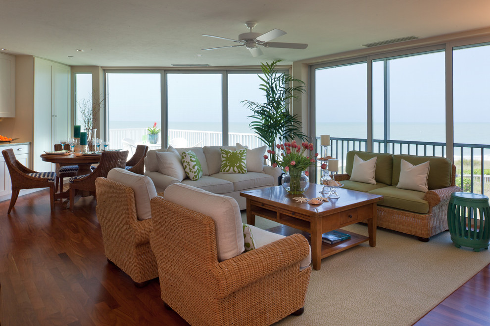 Modelo de salón para visitas abierto costero de tamaño medio sin chimenea con paredes blancas, suelo de madera en tonos medios y televisor retractable