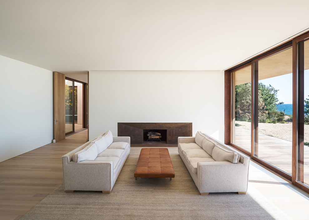 Modernes Wohnzimmer mit weißer Wandfarbe, braunem Holzboden, Kamin und braunem Boden in New York