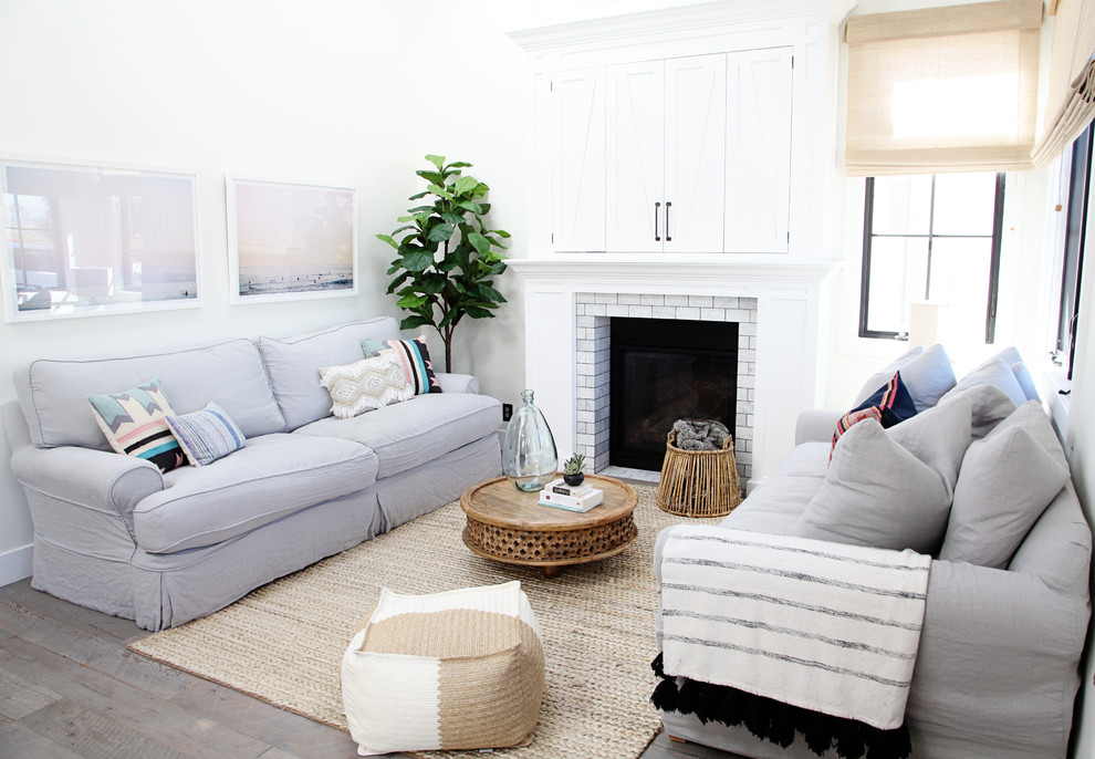 Design ideas for a nautical formal open plan living room in Los Angeles with white walls, a standard fireplace, a concealed tv and grey floors.
