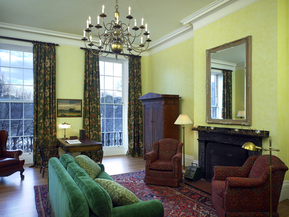 Großes, Repräsentatives, Abgetrenntes Klassisches Wohnzimmer mit gelber Wandfarbe, braunem Holzboden, Kamin und Kaminumrandung aus Stein in Boston