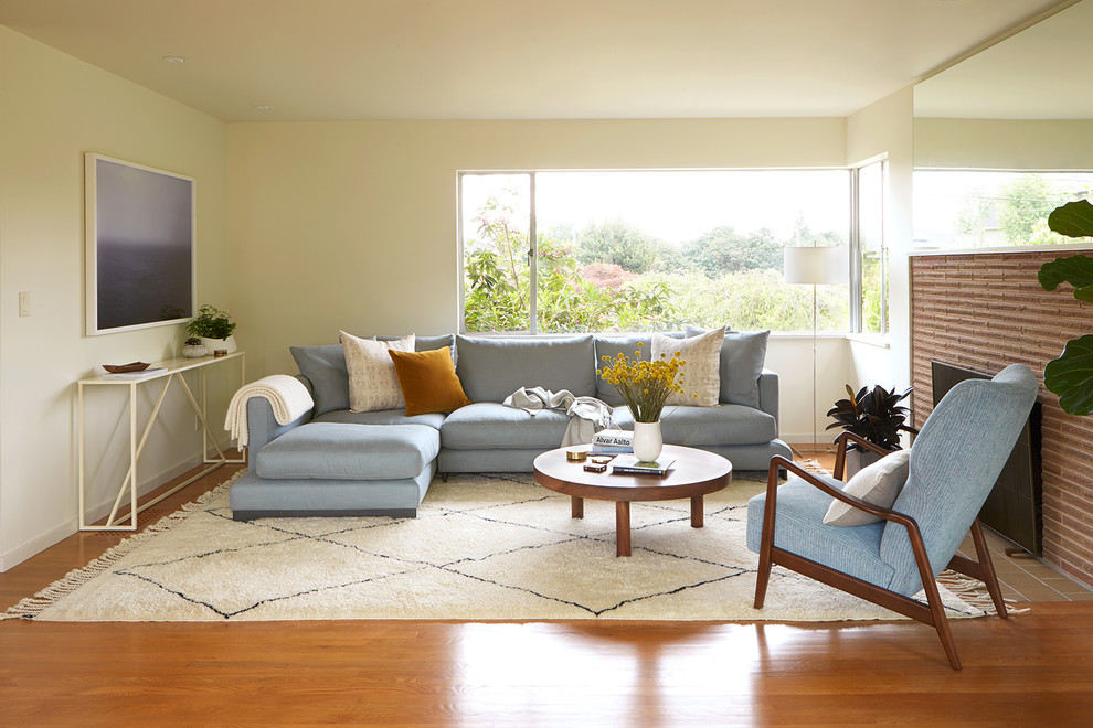 Источник вдохновения для домашнего уюта: гостиная комната в стиле ретро с белыми стенами, паркетным полом среднего тона, стандартным камином, фасадом камина из кирпича и оранжевым полом без телевизора