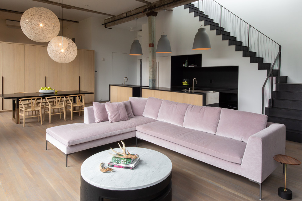 Exemple d'un salon mansardé ou avec mezzanine industriel de taille moyenne avec un mur blanc, un sol en bois brun, une salle de réception, aucun téléviseur, un sol marron, une cheminée ribbon et un manteau de cheminée en béton.