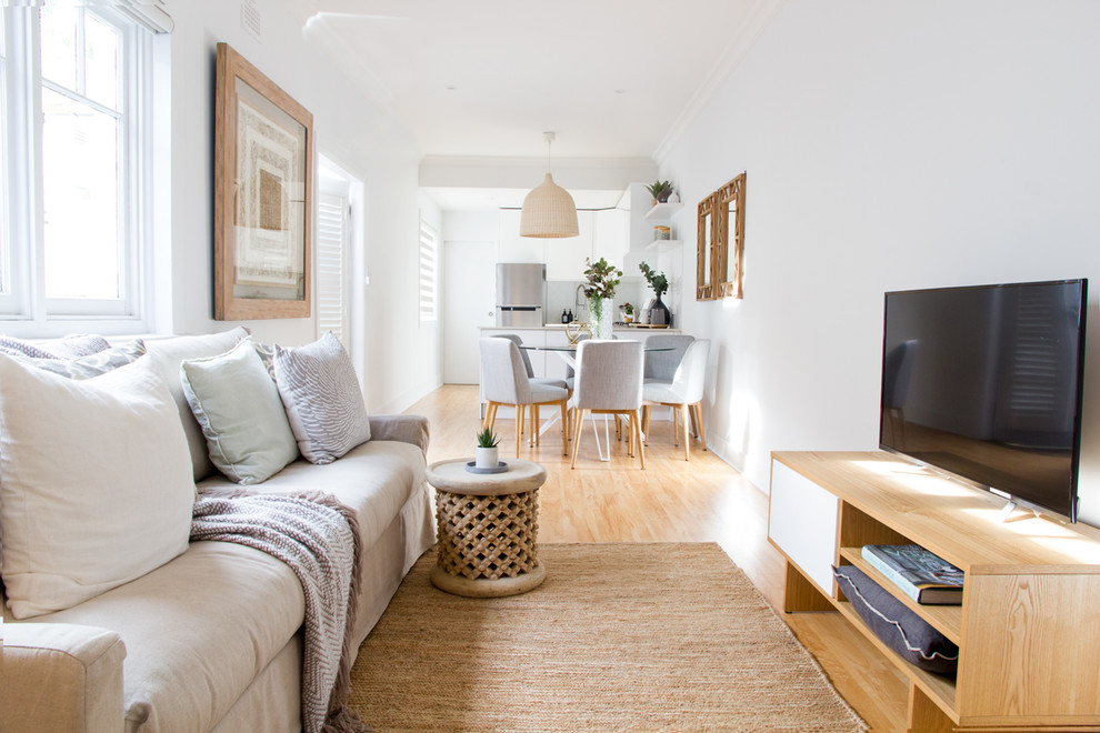Exempel på ett skandinaviskt allrum med öppen planlösning, med vita väggar, ljust trägolv och en fristående TV