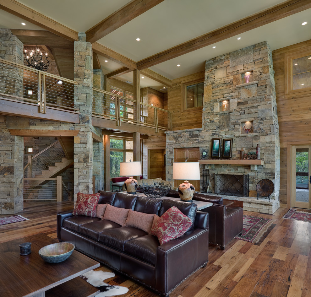 Uriges Wohnzimmer mit braunem Holzboden, Kamin und Kaminumrandung aus Stein in Charlotte