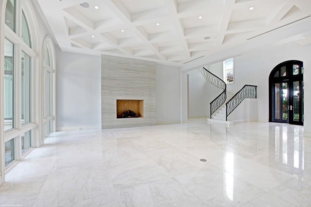 Идея дизайна: огромная парадная, открытая гостиная комната в средиземноморском стиле с белыми стенами, мраморным полом, стандартным камином и фасадом камина из плитки без телевизора