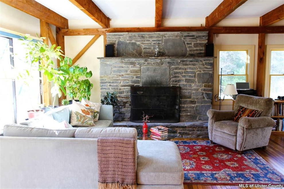 Example of a large eclectic open concept medium tone wood floor living room design in New York with white walls, a standard fireplace, a stone fireplace and no tv