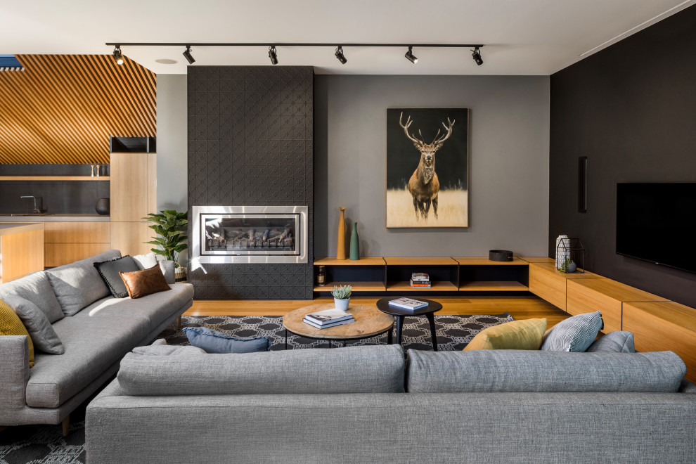 Cette image montre un salon design de taille moyenne et ouvert avec un mur noir, une cheminée ribbon, un manteau de cheminée en métal, un téléviseur fixé au mur, un sol marron et un sol en bois brun.