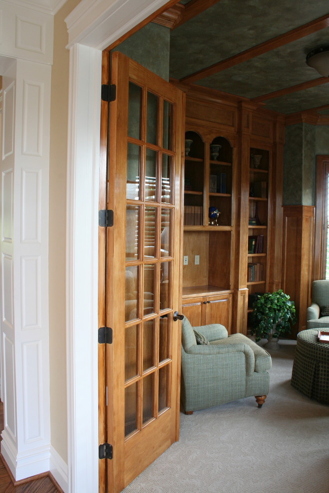 Cette image montre un salon traditionnel fermé avec une bibliothèque ou un coin lecture, un mur vert, moquette, aucune cheminée et un téléviseur encastré.