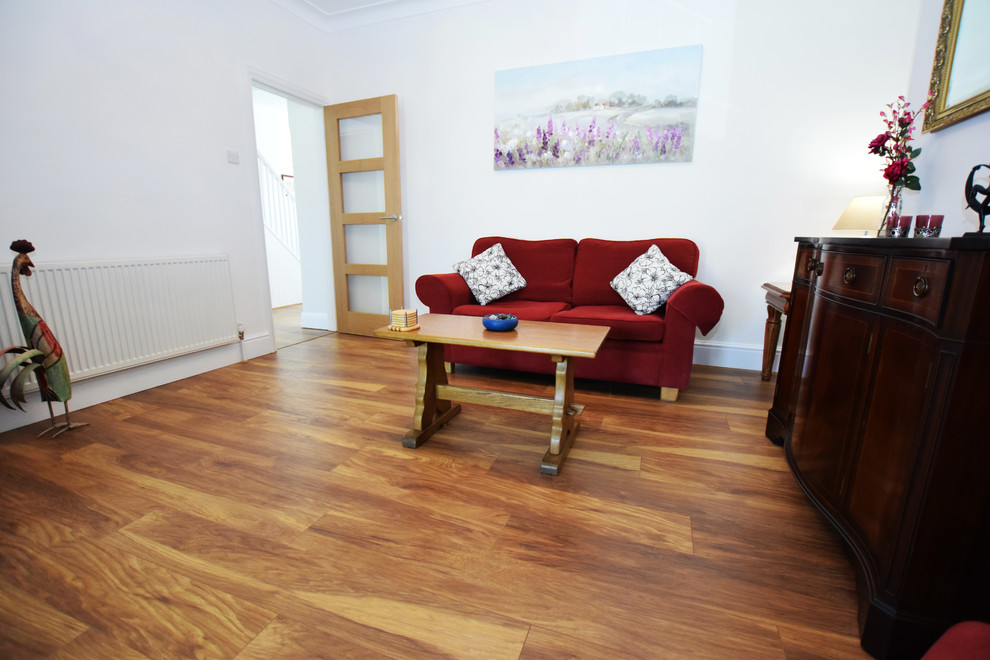 Diseño de salón para visitas cerrado clásico grande con paredes blancas, suelo laminado, televisor independiente y suelo marrón
