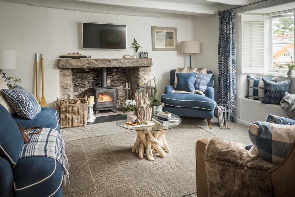 Inspiration for a small coastal formal enclosed living room in Devon with white walls, carpet, a wood burning stove, a stone fireplace surround, a wall mounted tv and grey floors.