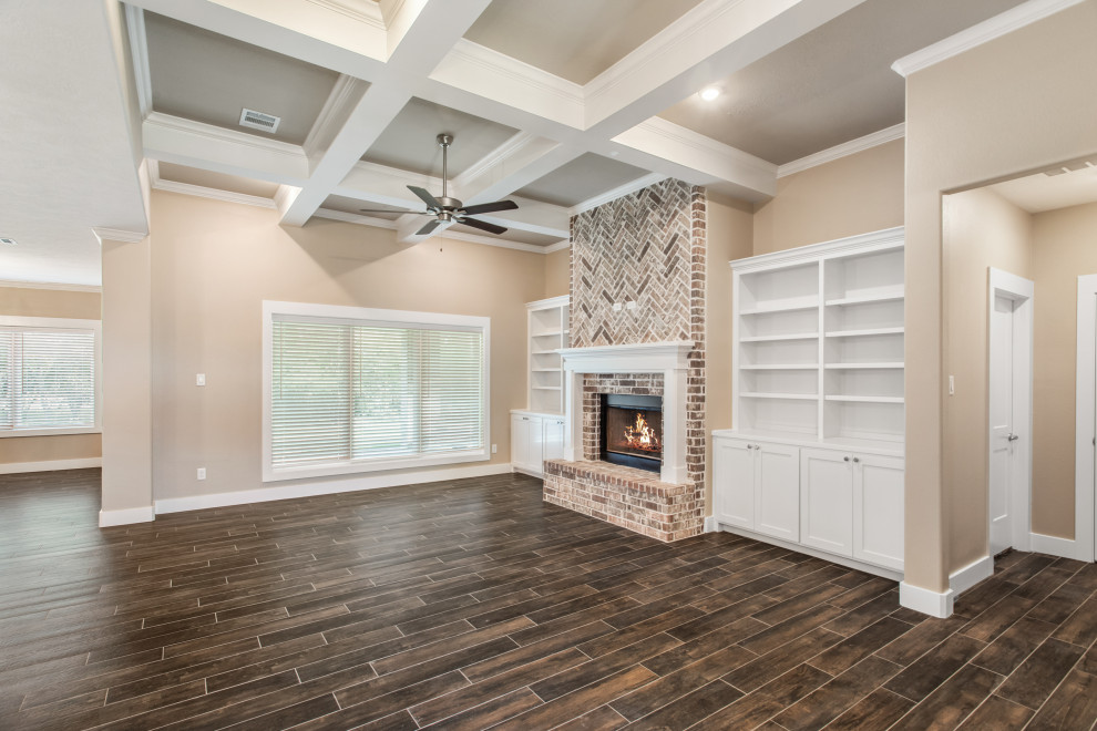 Rustikales Wohnzimmer mit beiger Wandfarbe, dunklem Holzboden, Kaminumrandung aus Stein und braunem Boden in Austin