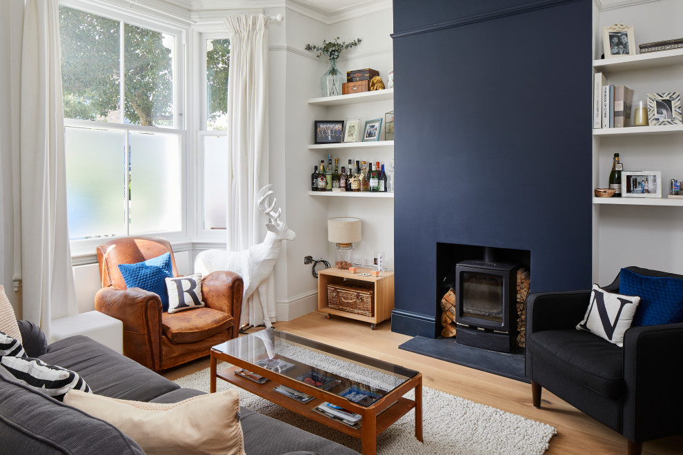 Immagine di un soggiorno design di medie dimensioni con pareti bianche, pavimento in legno massello medio, stufa a legna e pavimento marrone