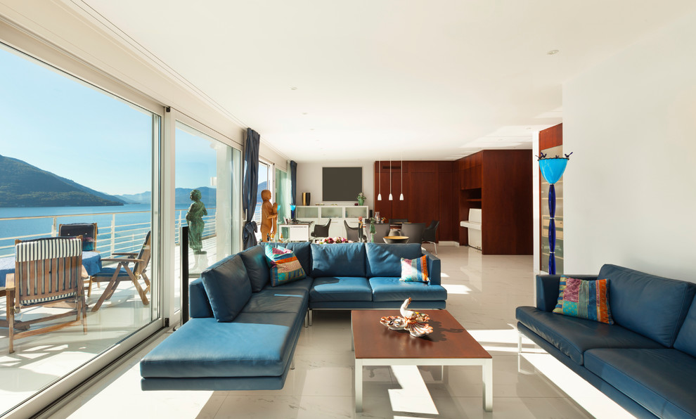 На фото: открытая гостиная комната в современном стиле с белыми стенами и синими шторами без камина