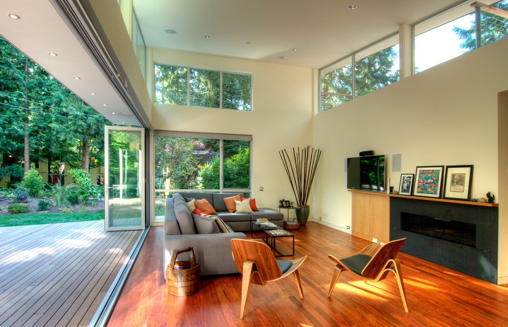 Cette photo montre un salon tendance avec un mur beige, un sol en bois brun, une cheminée ribbon et un téléviseur fixé au mur.