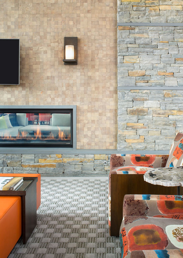 デンバーにあるラグジュアリーな巨大なラスティックスタイルのおしゃれなLDK (ベージュの壁、カーペット敷き、両方向型暖炉、石材の暖炉まわり) の写真