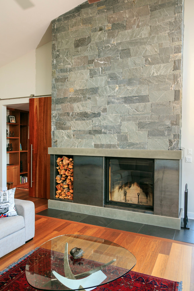 Medium sized modern formal open plan living room in Vancouver with white walls, medium hardwood flooring, a standard fireplace and a concrete fireplace surround.