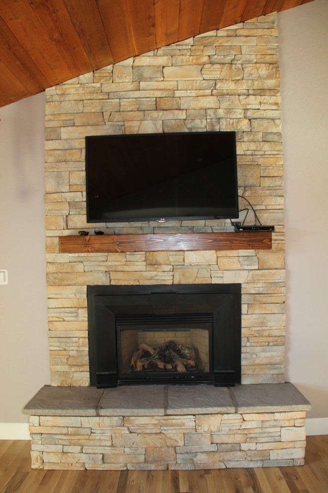This is an example of a medium sized contemporary open plan living room in Phoenix with medium hardwood flooring, a standard fireplace, a stone fireplace surround and a wall mounted tv.