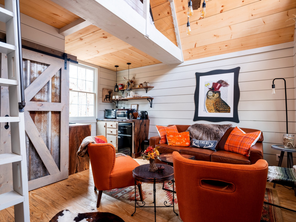 Inspiration for a small rustic medium tone wood floor, brown floor, vaulted ceiling and shiplap wall living room remodel with white walls