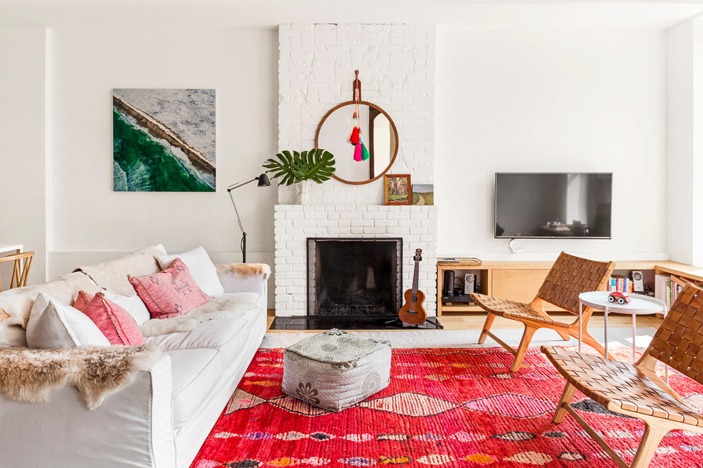 Repräsentatives Eklektisches Wohnzimmer mit weißer Wandfarbe, hellem Holzboden, Kamin, Kaminumrandung aus Backstein, TV-Wand und braunem Boden in New York