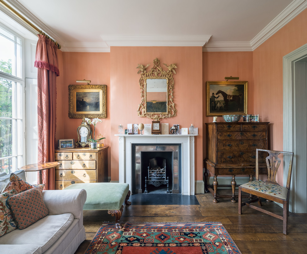 Großes, Repräsentatives, Abgetrenntes, Fernseherloses Klassisches Wohnzimmer mit oranger Wandfarbe, dunklem Holzboden, Kamin und Kaminumrandung aus Metall in London