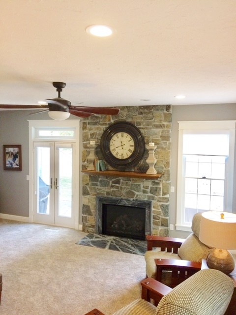 This is an example of a classic living room in Cedar Rapids with a standard fireplace and a stone fireplace surround.